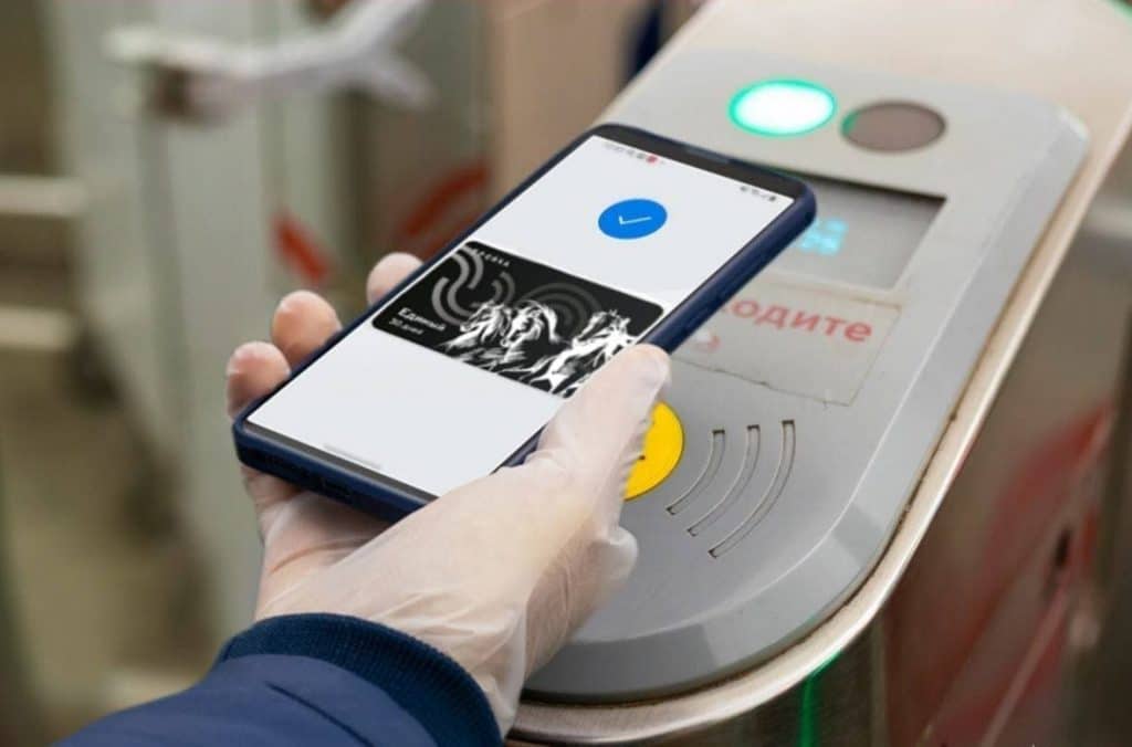 Hand holding smartphone with virtual Troika card at gate.